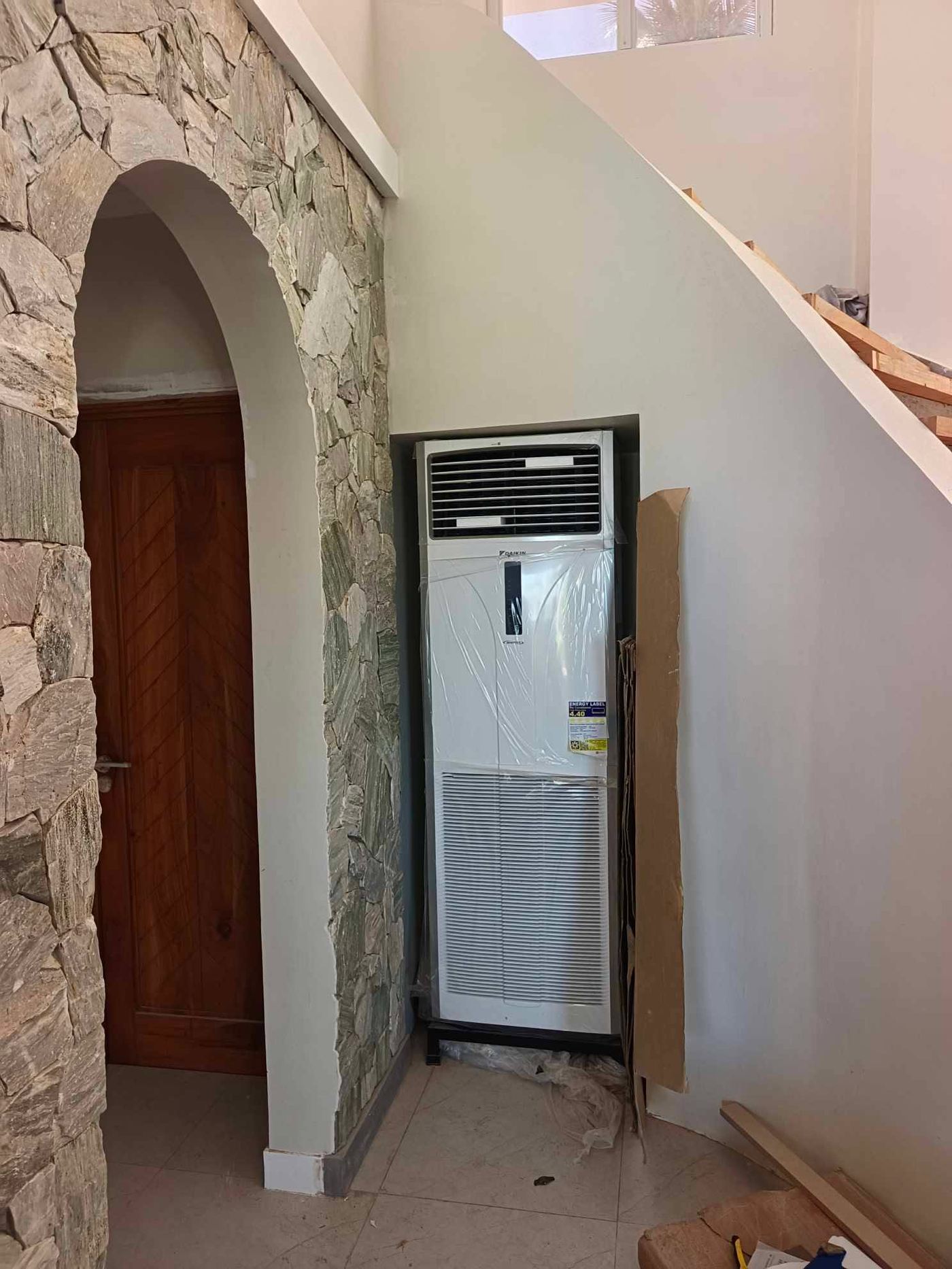 Daikin floor-standing unit set against a stone arch beside a timber door